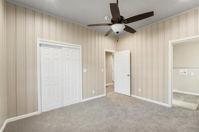 unfurnished bedroom with crown molding, ceiling fan, baseboards, carpet, and a closet