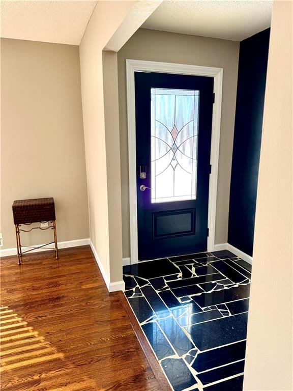 entrance foyer with dark wood-type flooring and a textured ceiling