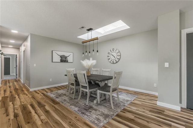 dining room with wood-type flooring and a skylight