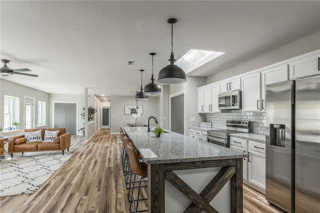 kitchen featuring a skylight, stainless steel appliances, and white cabinetry