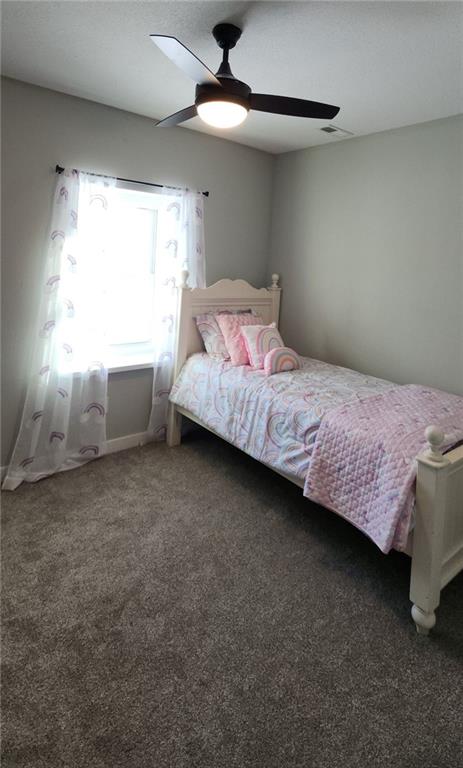 bedroom with ceiling fan and dark carpet