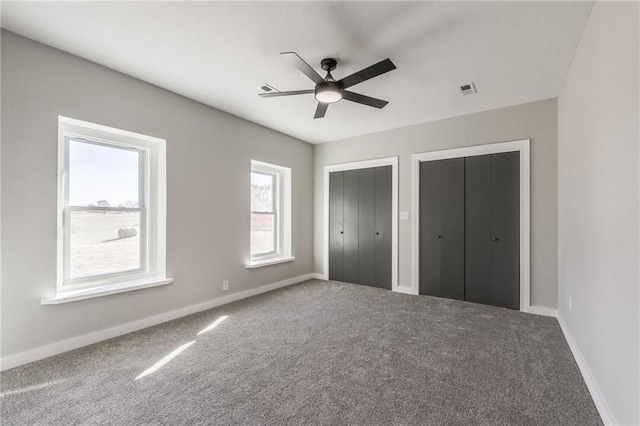 unfurnished bedroom featuring multiple closets, carpet, and ceiling fan