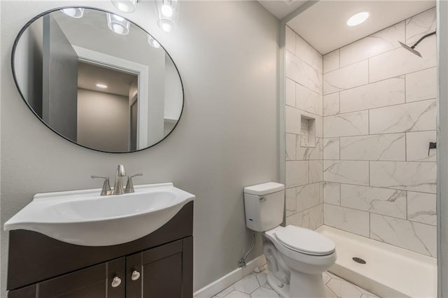 bathroom featuring toilet, vanity, and a tile shower