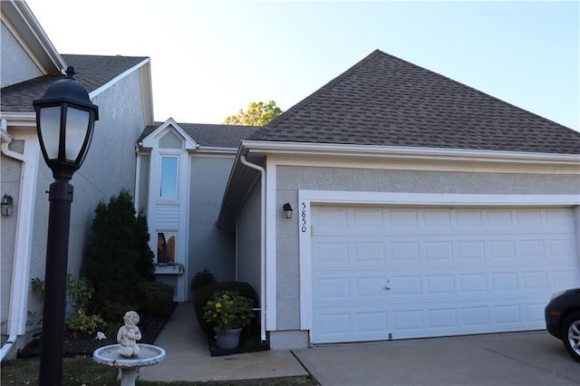 5850 Park Cir, Shawnee, KS 66216 - view of side of property with stucco siding, an attached garage, roof with shingles, and concrete driveway