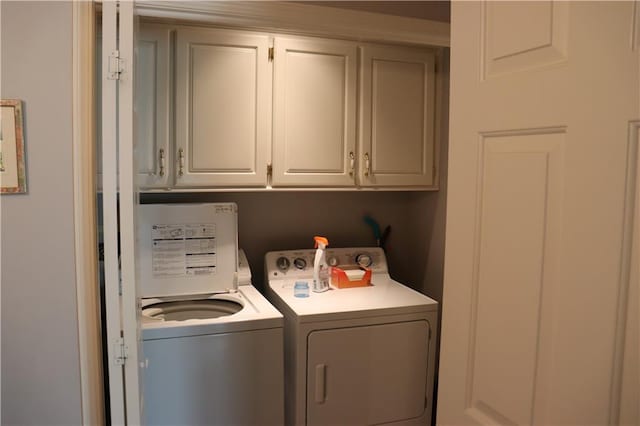 clothes washing area with washing machine and dryer and cabinets