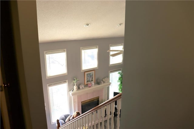 stairway with a textured ceiling, a tile fireplace, and a wealth of natural light