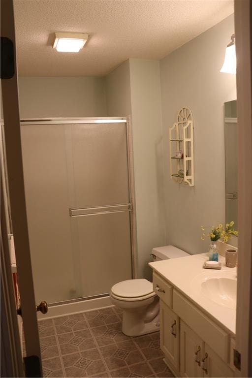 bathroom with vanity, toilet, a textured ceiling, and a shower with door