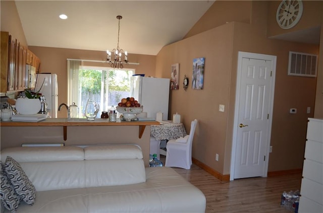 interior space featuring sink, a chandelier, vaulted ceiling, and light hardwood / wood-style flooring