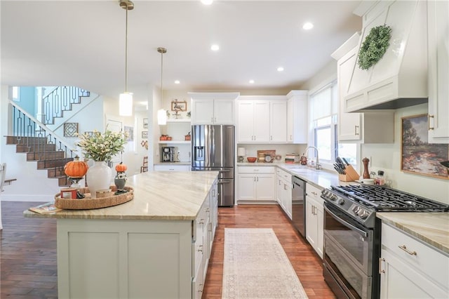 kitchen featuring a center island, hardwood / wood-style flooring, stainless steel appliances, and light stone counters