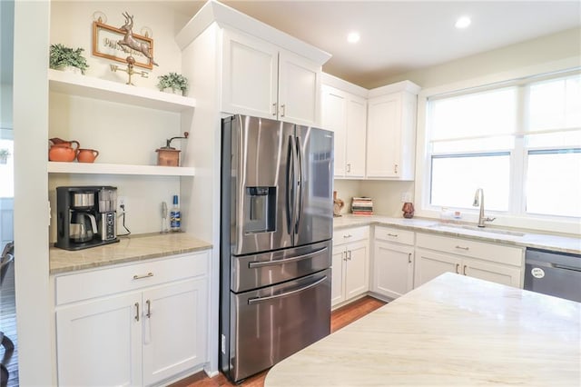 kitchen featuring wood-type flooring, light stone countertops, sink, stainless steel appliances, and white cabinets