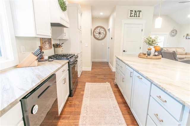 kitchen featuring appliances with stainless steel finishes, premium range hood, white cabinetry, wood-type flooring, and pendant lighting