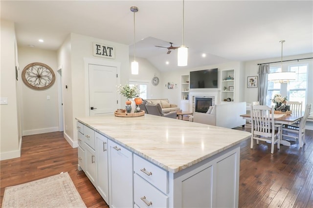 kitchen featuring white cabinets, hanging light fixtures, dark hardwood / wood-style flooring, light stone countertops, and vaulted ceiling