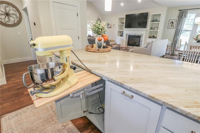 kitchen with vaulted ceiling, light stone countertops, dark hardwood / wood-style floors, and white cabinetry