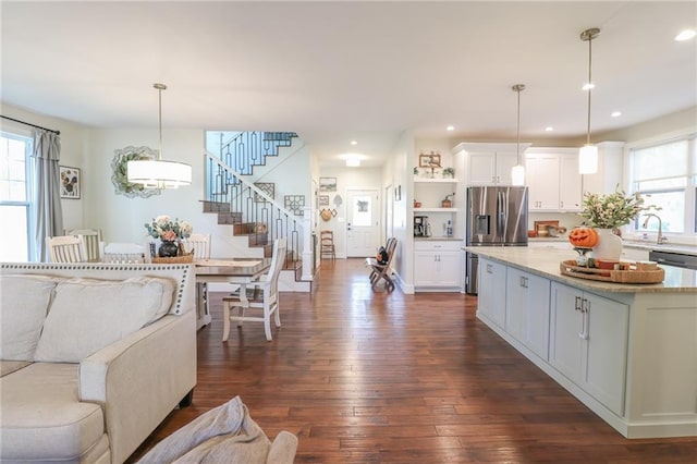 kitchen featuring a kitchen island, dark hardwood / wood-style floors, hanging light fixtures, white cabinetry, and appliances with stainless steel finishes