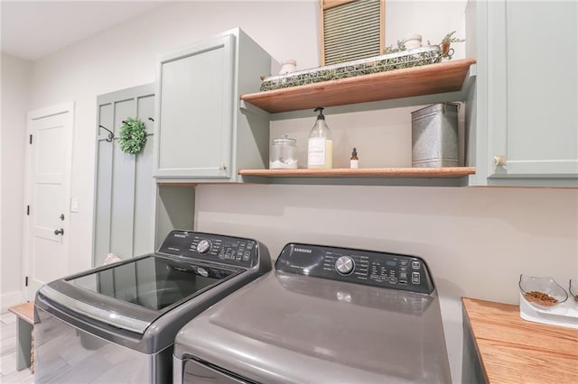 washroom featuring hardwood / wood-style floors, separate washer and dryer, and cabinets