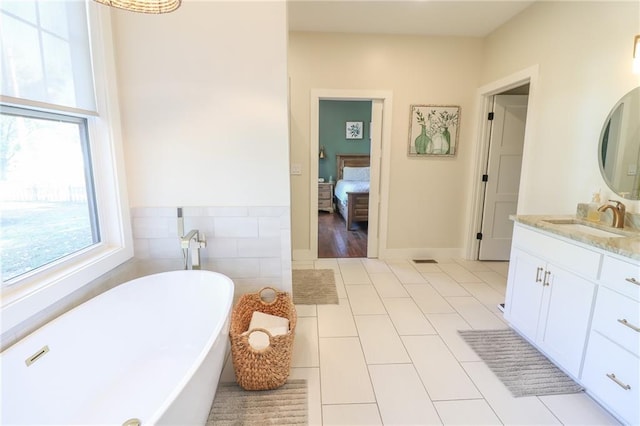 bathroom with tile walls, vanity, tile patterned floors, and a bathing tub