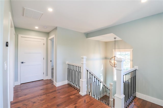 hall featuring dark wood-type flooring and a notable chandelier