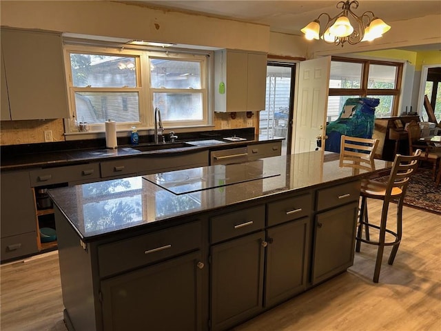 kitchen featuring dark stone countertops, light hardwood / wood-style flooring, pendant lighting, and a kitchen island