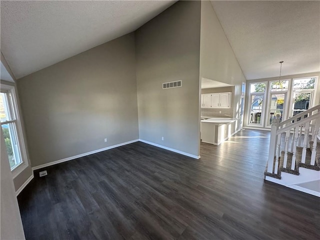 unfurnished living room featuring a textured ceiling, dark hardwood / wood-style floors, high vaulted ceiling, and plenty of natural light