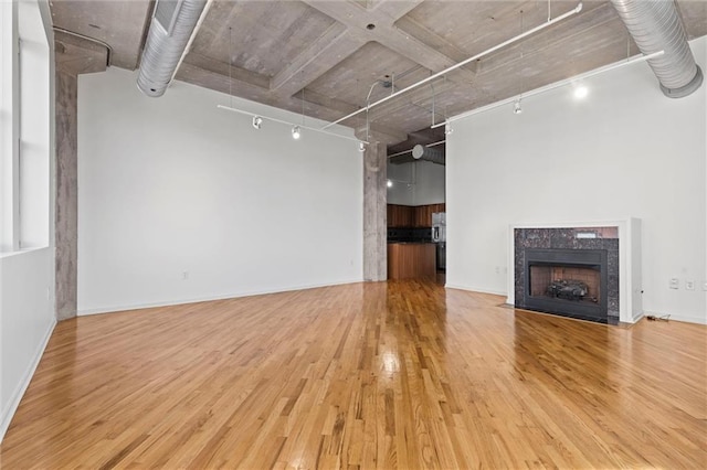 unfurnished living room featuring track lighting, a fireplace, and light hardwood / wood-style floors