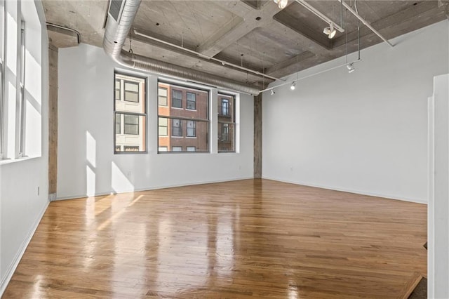 unfurnished room featuring rail lighting and hardwood / wood-style flooring