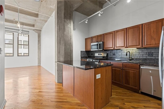 kitchen with light hardwood / wood-style floors, stainless steel appliances, decorative backsplash, and sink