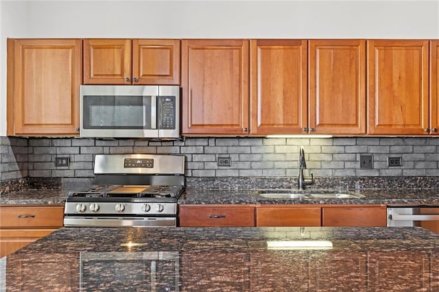 kitchen with sink, decorative backsplash, stainless steel appliances, and dark stone counters