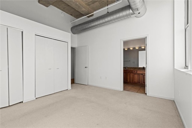 unfurnished bedroom with ensuite bath and light colored carpet