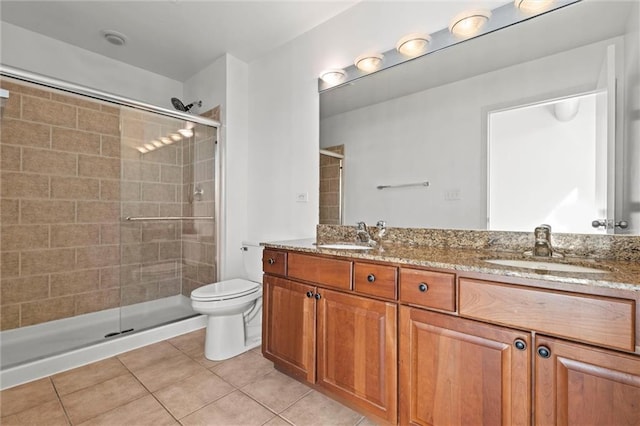 bathroom with toilet, tile patterned flooring, vanity, and a shower with door