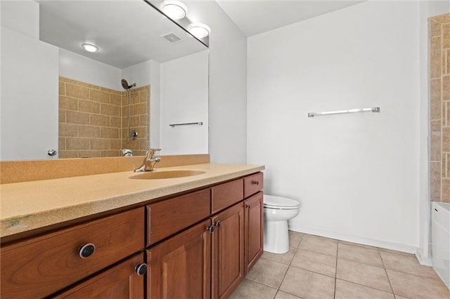 bathroom with vanity, a tile shower, toilet, and tile patterned flooring