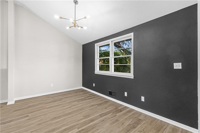 spare room with a notable chandelier, wood-type flooring, and lofted ceiling