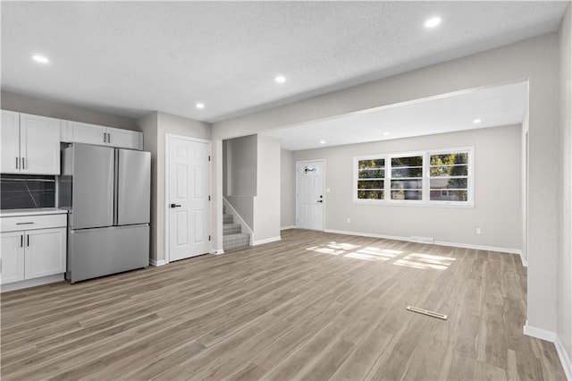 kitchen featuring backsplash, a textured ceiling, light hardwood / wood-style floors, white cabinets, and white refrigerator