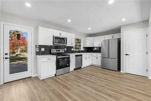 kitchen featuring decorative backsplash, white cabinetry, light hardwood / wood-style flooring, sink, and stainless steel appliances