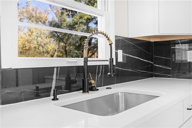 room details featuring white cabinetry, backsplash, and sink