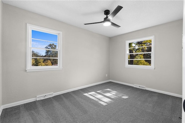 spare room featuring ceiling fan and dark colored carpet