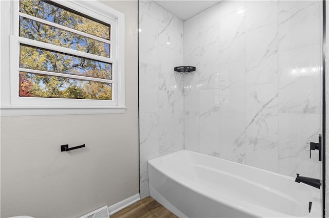 bathroom with a healthy amount of sunlight, tiled shower / bath, and hardwood / wood-style floors