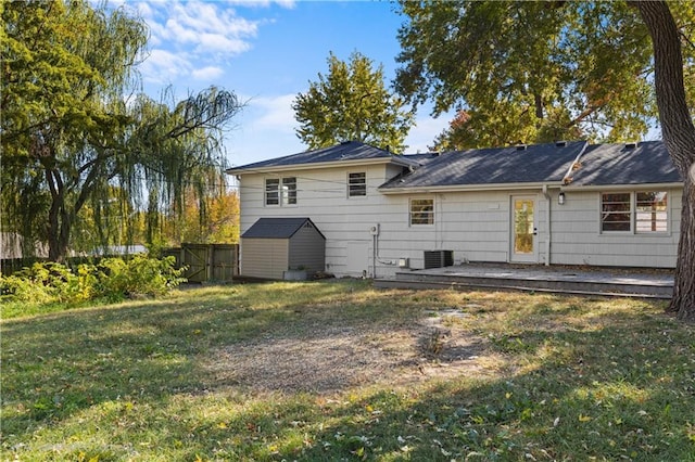 back of house featuring a storage shed, central AC, and a lawn