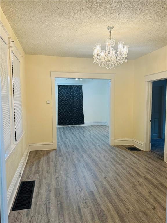 spare room featuring a textured ceiling, a chandelier, and hardwood / wood-style floors