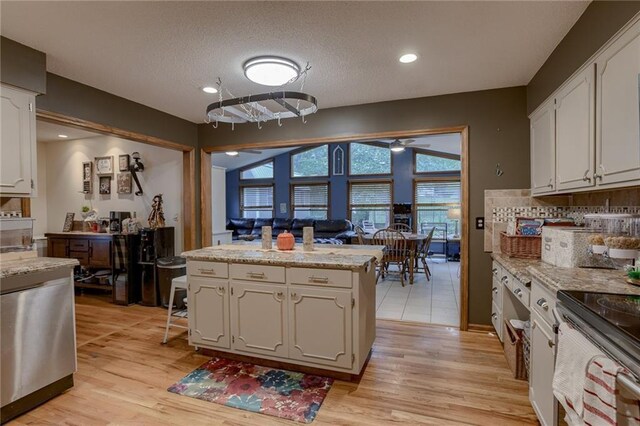 kitchen featuring light hardwood / wood-style flooring, light stone countertops, white cabinetry, a textured ceiling, and ceiling fan