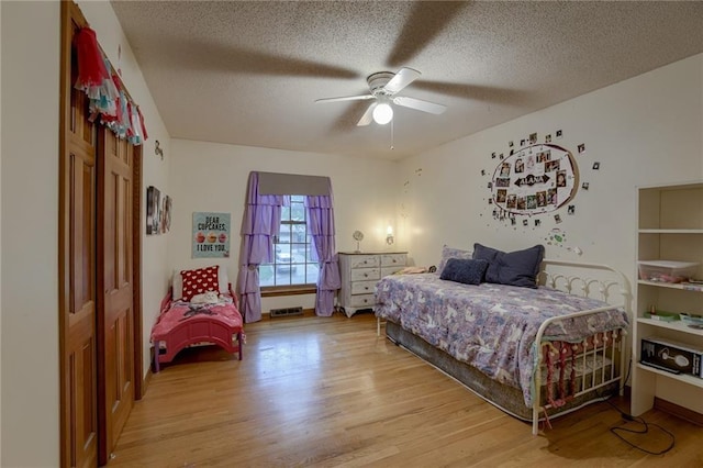 bedroom with a closet, a textured ceiling, light wood-type flooring, and ceiling fan