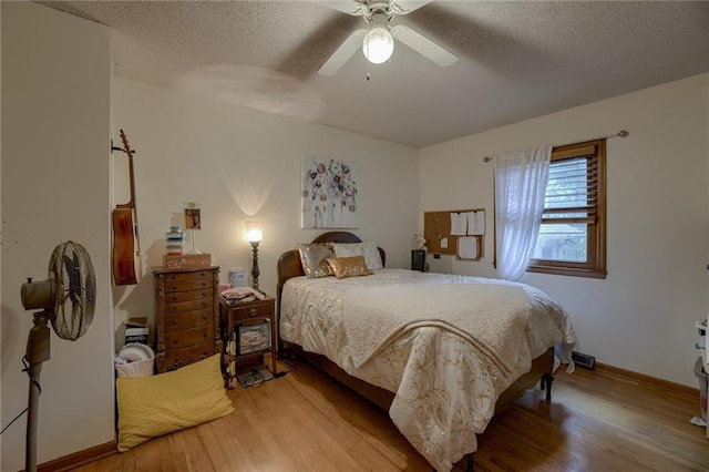 bedroom featuring ceiling fan, wood-type flooring, and a textured ceiling