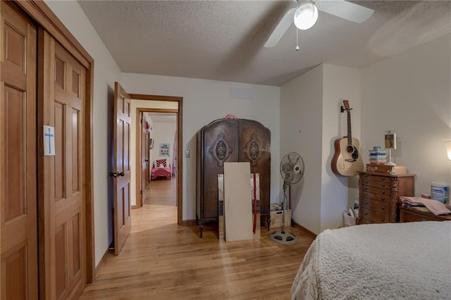 bedroom with light hardwood / wood-style flooring, a textured ceiling, and ceiling fan