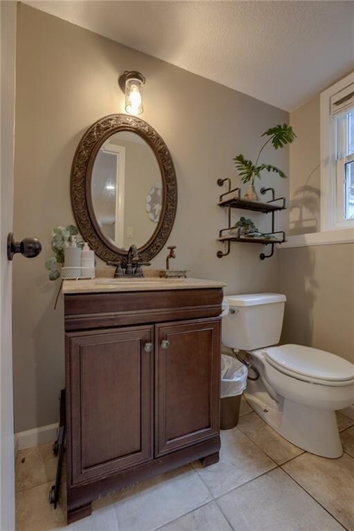 bathroom featuring vanity, a textured ceiling, toilet, and tile patterned flooring