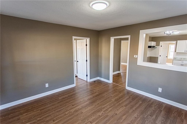 empty room with a textured ceiling and dark hardwood / wood-style flooring