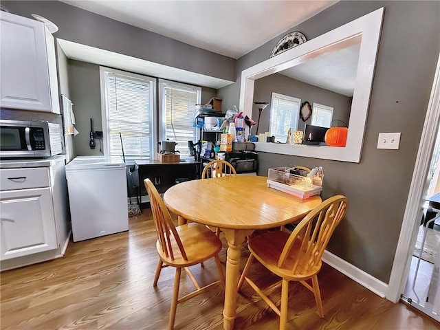 dining room featuring light wood-type flooring, washer / clothes dryer, and plenty of natural light