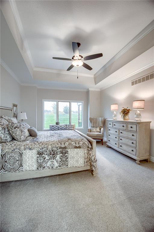 bedroom with visible vents, ornamental molding, carpet flooring, and a tray ceiling