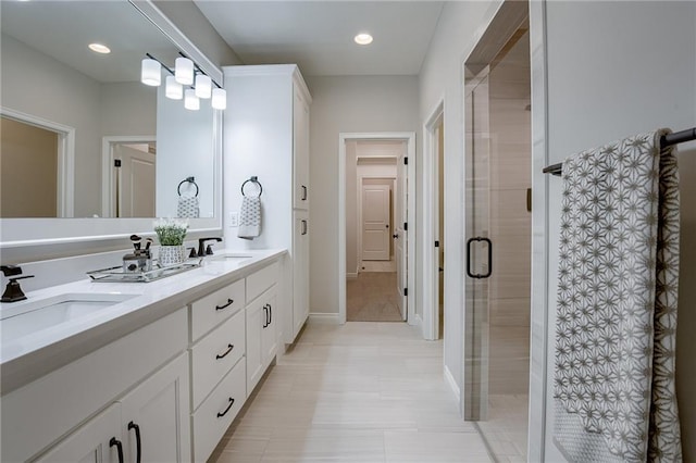 full bathroom with double vanity, recessed lighting, a stall shower, and a sink