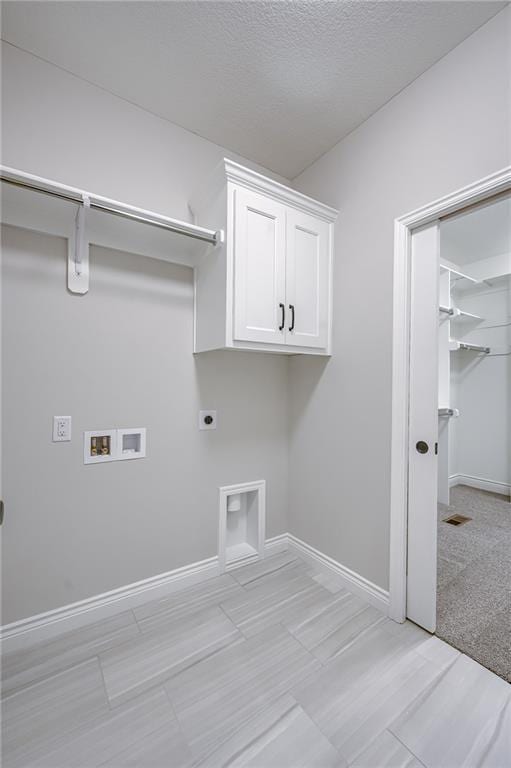 clothes washing area featuring baseboards, hookup for a washing machine, cabinet space, and hookup for an electric dryer