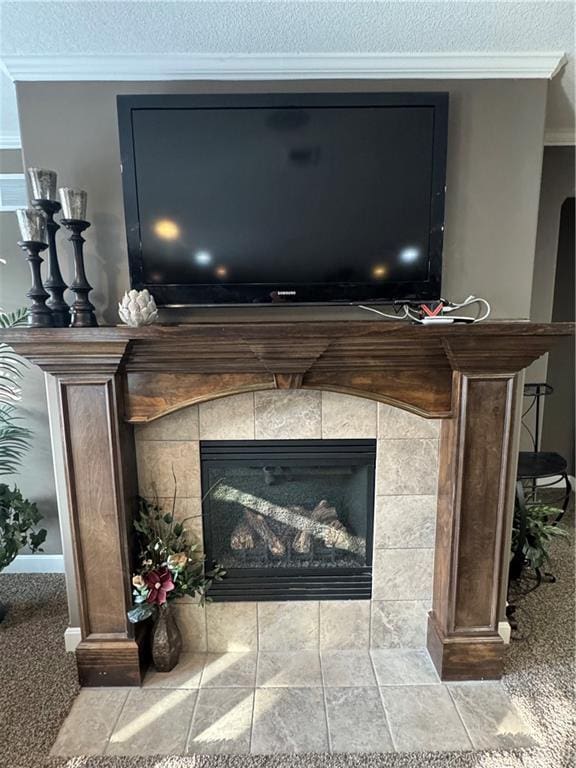 room details featuring a tiled fireplace, crown molding, and a textured ceiling