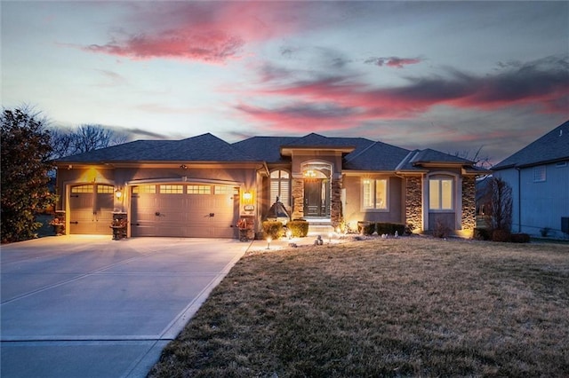 prairie-style house with a garage, concrete driveway, a lawn, and stucco siding